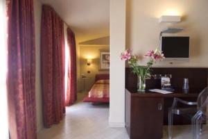 a bedroom with a bed and a vase of flowers on a desk at Hotel Touring in Fiorano Modenese