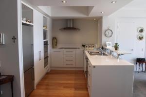 una cucina con mobili bianchi e un piano di lavoro di Picton Waterfront Oxley's Luxury Apartment a Picton