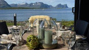 a table with glasses and wine bottles on it at Bergnes Lodge in Senja