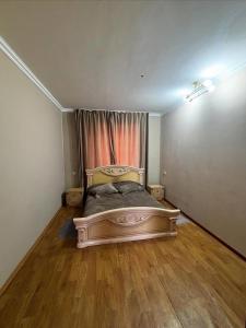 a bedroom with a bed in a room with wooden floors at Дом твоей силы in Talghar
