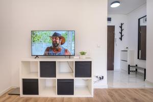 a television on a white stand in a living room at Deda Studio w. Smart TV · AC · washing machine in Bucharest