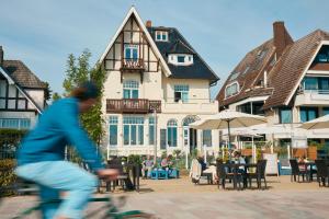 a man riding a bike in front of a building at Lieblingsplatz Hotel Strandperle in Travemünde
