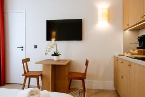 a kitchen with a table and two chairs and a tv on the wall at Résidence Monceau Jadin in Paris