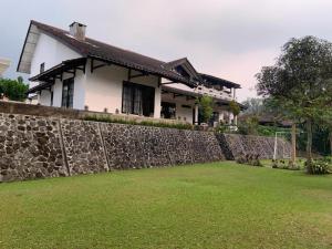 a house with a stone wall and a yard at Hotel Kay Terrace in Campaka