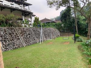 a swing set in a yard next to a stone wall at Hotel Kay Terrace in Campaka