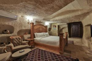 a bedroom with a bed and a chair at Elika Cave Suites Cappadocia, Curio Collection by Hilton in Ortahisar +281 photos