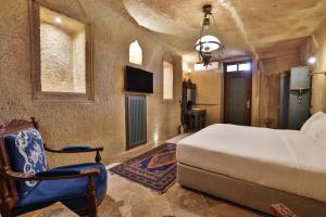 a bedroom with a bed and a chair at Elika Cave Suites Cappadocia, Curio Collection by Hilton in Ortahisar
