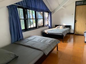 two beds in a room with windows at Hotel Kay Terrace in Campaka