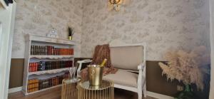 a room with a chair and a book shelf with books at La Romantique du Château in Gaillan-en-Médoc