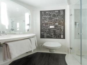 a bathroom with a toilet and a sink and a mirror at ibis London Barking in Barking +47 photos