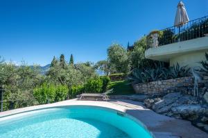 a swimming pool in front of a house at ApartmentsGarda - Villa Giada in Torri del Benaco