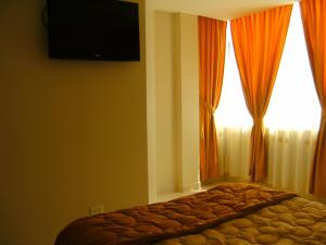 a bedroom with a bed with a television on the wall at Hostal Fevilamir in Ibarra
