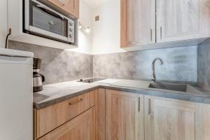 a kitchen with wooden cabinets and a sink at Studio meublé in Saint-Rémy-de-Provence