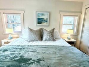 a bedroom with a large bed with two windows at Peaceful Redding Cottage Retreat in Redding