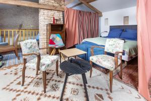 a bedroom with a bed and two chairs and a table at La Grange des zarts in Champagné-le-Sec