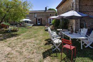a table with an umbrella and chairs in a yard at La Grange des zarts in Champagné-le-Sec