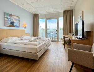 a bedroom with a bed and a desk and a television at Bodensee Yachthotel Schattmaier in Kressbronn am Bodensee