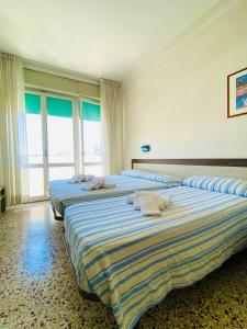two beds sitting in a room with windows at Hotel Europa in Gabicce Mare