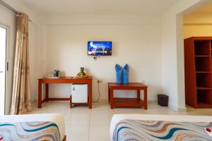 a room with a bed and a desk and a tv at Malika Blue Hotel Nungwi, Zanzibar in Banda Kuu