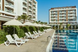 a row of chairs and umbrellas next to a swimming pool at Greenwood Suites Resort in Lara