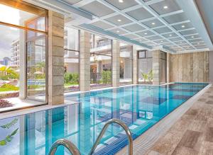a swimming pool in a building with a large window at Greenwood Suites Resort in Lara +49 photos