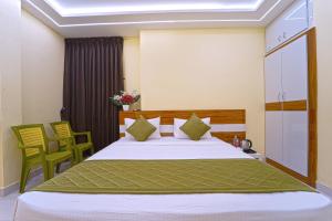 a bedroom with a large bed with green chairs at I&S Residency in Rāmanāthapuram