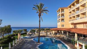 a view of a hotel with a palm tree and a swimming pool at Thalassa Boutique Hotel & Spa in Paphos