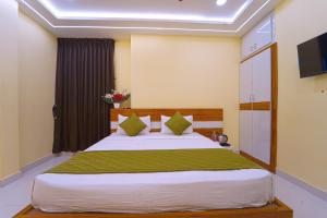a bedroom with a large bed with green sheets at I&S Residency in Rāmanāthapuram