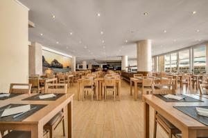 a restaurant with wooden tables and chairs and windows at Albufeira Sol Hotel & Spa in Albufeira