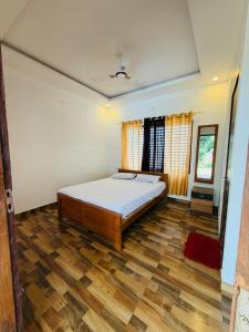a bedroom with a bed and a wooden floor at BIG INN Resort in Mattanūr