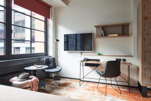 a room with a desk and two chairs and a tv at hood house in Hamburg