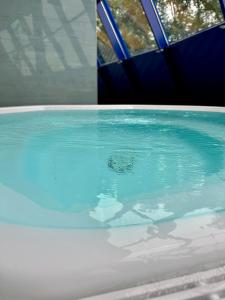 a bath tub filled with blue water next to a window at Bodensee Yachthotel Schattmaier in Kressbronn am Bodensee