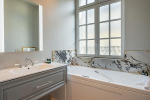 a bathroom with a tub and a sink and a window at Hôtel Elysia by Inwood Hotels in Paris