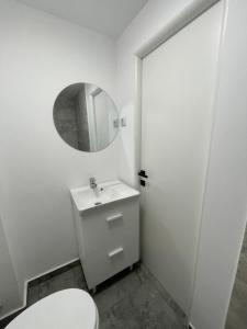 a white bathroom with a toilet and a mirror at The Urban Nest apartament in Giurgiu