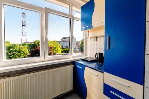 a kitchen with blue cabinets and two windows at Walter Waves Private Apartment with Balcony and Self Check-In in Costinesti