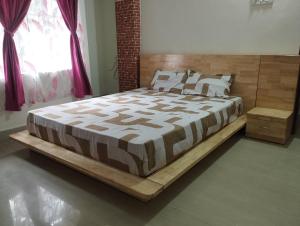 a bedroom with a large bed with a wooden frame at Phalchaa Stay in Jaigaon