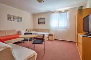 a room with two beds and a table and a tv at Penzion Aida Ostrava in Ostrava