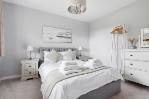 a white bedroom with a bed with white blankets and pillows at Glenisla, Aviemore, fantastic location with sauna and hot tub in Aviemore