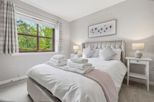 a white bedroom with a bed with towels on it at Glenisla, Aviemore, fantastic location with sauna and hot tub in Aviemore
