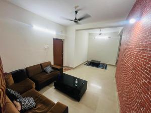 a living room with a couch and a brick wall at Phalchaa Stay in Jaigaon
