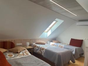 a attic room with three beds and a window at Männi hoovimaja in Pärnu