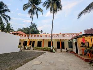 a building with palm trees in the background at Second Home Stays at Arnav Cottages Alibag in Alibaug