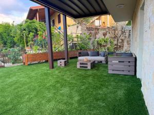 a patio with green grass and a couch and a table at Le AVRA MONTIS in Galata