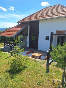 a white building with a picnic table and a bench at Planinska kuća Radulović in Goč +44 photos