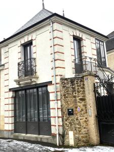 a building with black doors and a stone wall at Relais Fléchois in La Flèche
