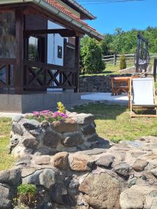 a stone wall in front of a building with a bench at Planinska kuća Radulović in Goč