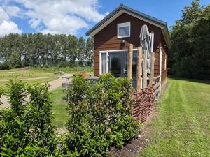 a small building with a sign on the side of it at De Meerkoet Tiny House Tussen de Dijken in Driewegen