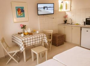 a kitchen with a table and a tv on the wall at Bright 2BR Apt Kitchenette Pool 3 in Gouvia