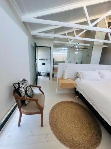 a bedroom with a bed and a chair and a mirror at Sunset Villa Herolds Bay in Herolds Bay