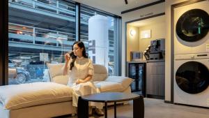 a woman sitting on a couch talking on a cell phone at Anook Stay Daejeon Daeheung in Daejeon